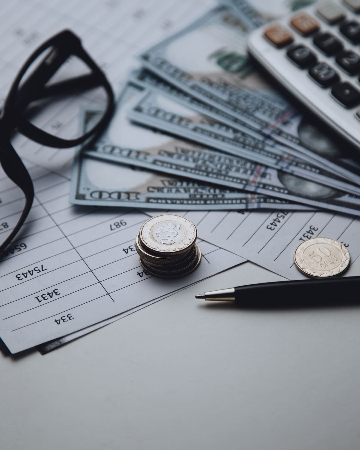 Stacks of cash beside a calculator and a glowing spreadsheet